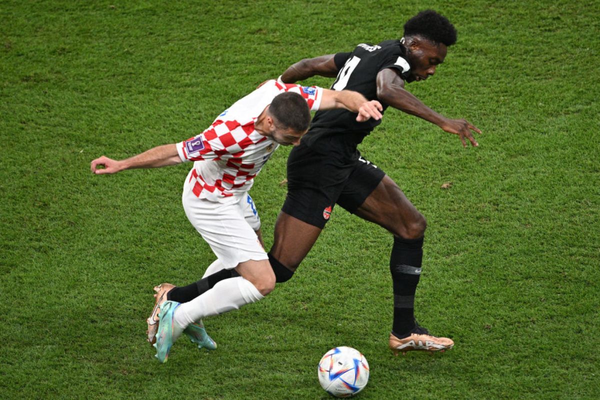 Alphonso Davies of Canada battles for possession with Josip Juranovic of Croatia