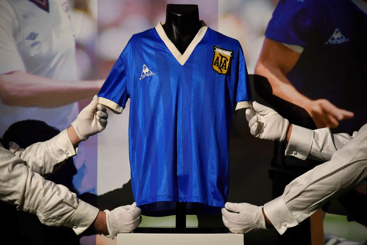 Art handlers pose with the shirt worn by Argentinian soccer player Diego Maradona in the 1986 World Cup, ahead of it being auctioned by Sotheby's, in London, Britain, April 20, 2022. 