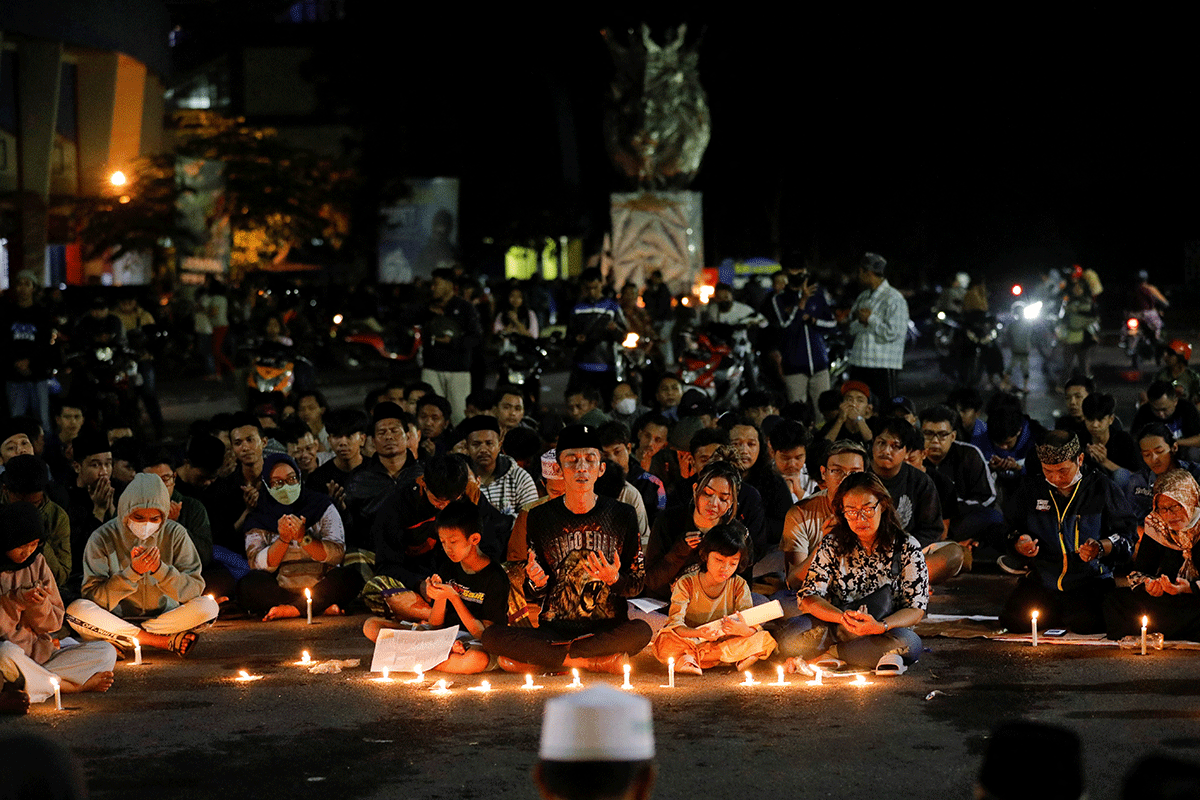 Arema football club supporters pray during a vigil outside the Kanjuruhan stadium to pay condolence to the victims on Sunday.