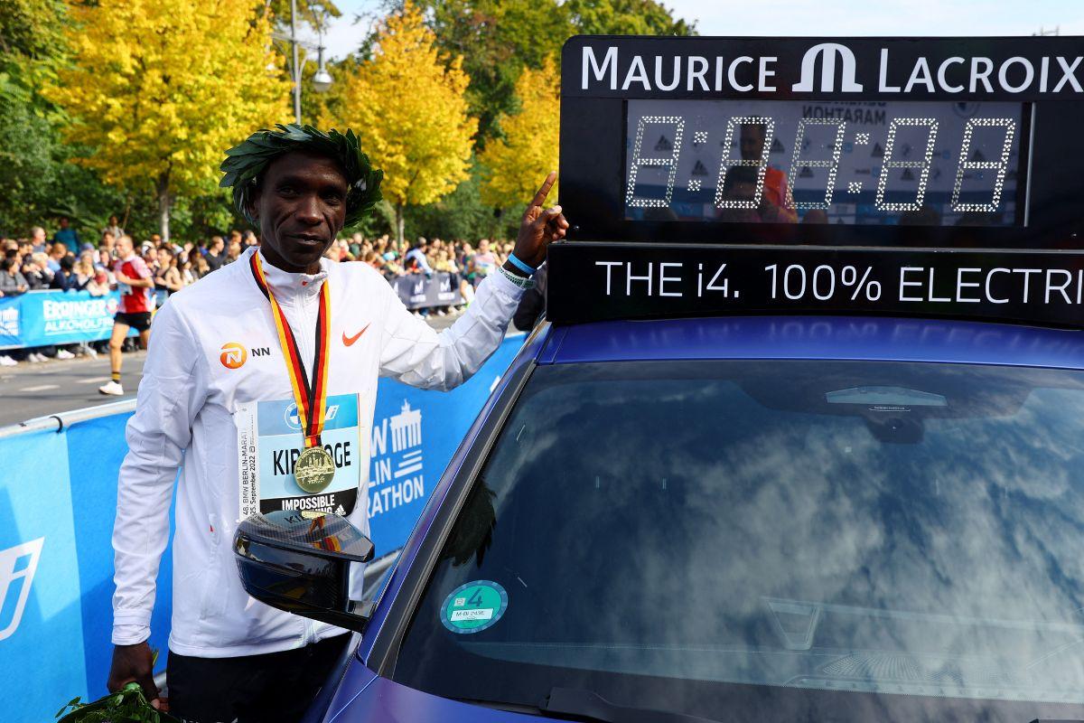 Kenya's Eliud Kipchoge celebrates winning the Berlin Marathon alongside a clock showing his World Record breaking time