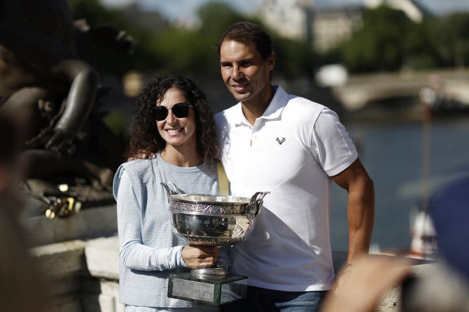 Rafael Nadal poses on the Alexandre III bridge with his wife Maria Francisca Perello and the trophy after winning the men's singles French Open title on June 6, 2022.