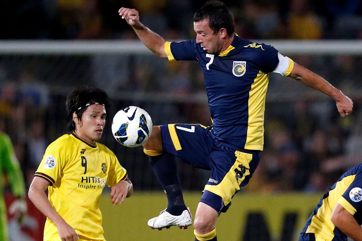 tral Coast Mariners player John Hutchinson (R) jumps to kick the ball next to Masato Kudo