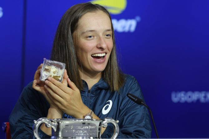 Iga Swiatek is all smiles as she pulls out a piece tiramisu from the trophy during a news conference following her victory over Ons Jabeur in the US Open women’s singles final on Saturday.