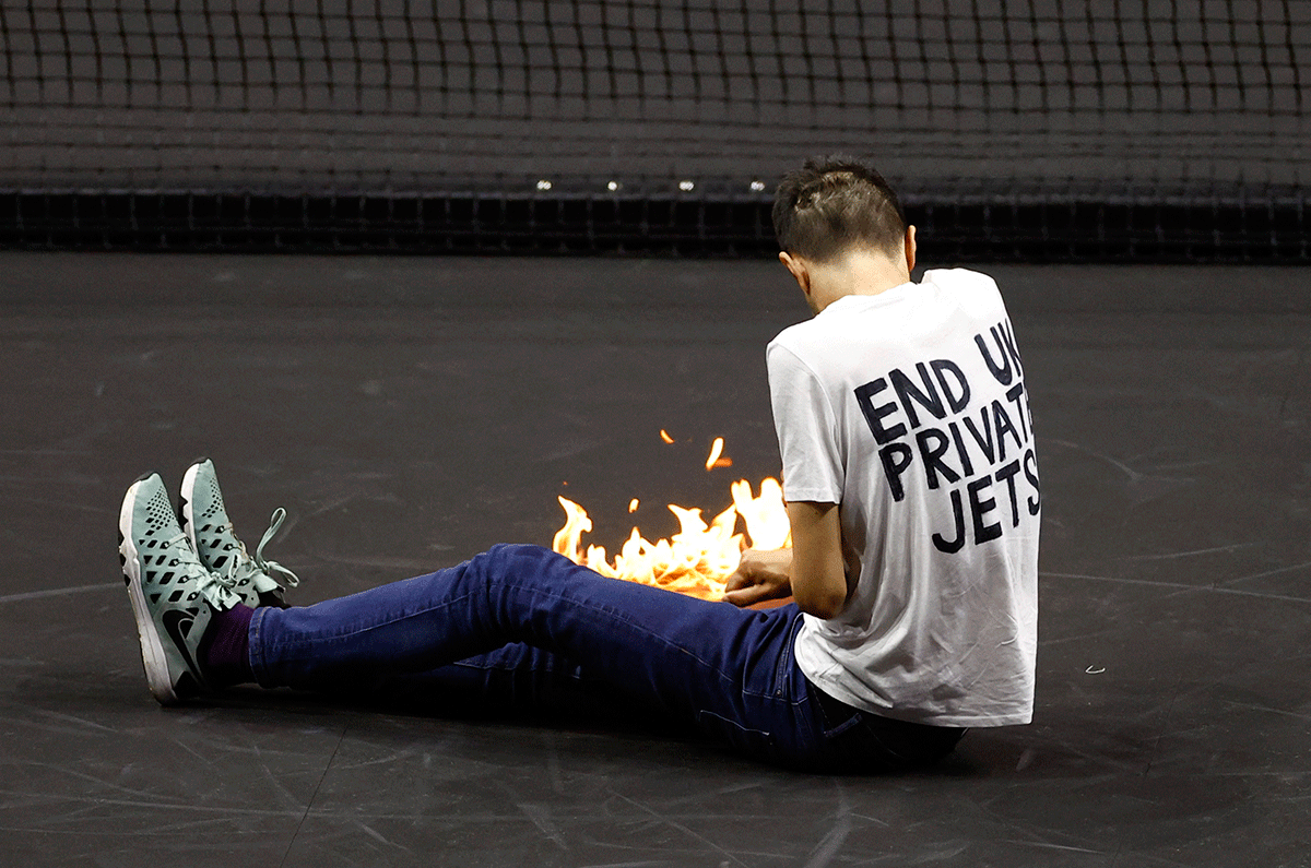 A protester lights a fire on the court during the Laver Cup match between Team Europe's Stefanos Tsitsipas and Team World's Diego Schwartzman at the 02 Arena, London, Britain, on Friday
