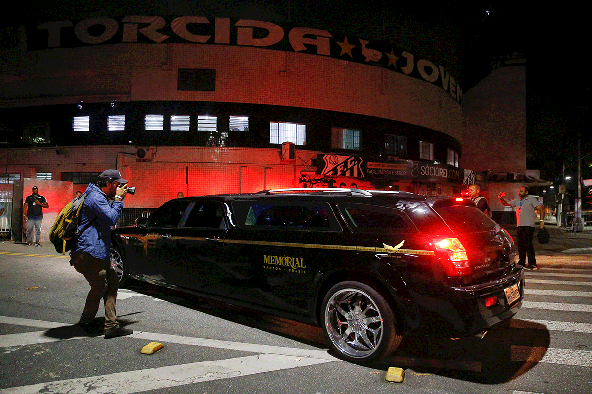 Un hombre toma una foto del vehículo que transportaba el cuerpo de la leyenda del fútbol brasileño Pelé, en el estadio Vila Belmiro el lunes.