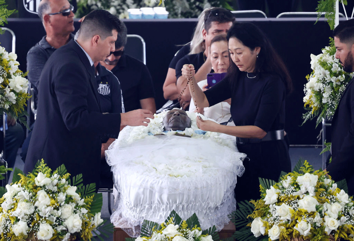 Pele's wife Marcia Aoki (2nd from right) places a rosary on Pele's coffin in Urbano Caldeira Stadium at his funeral in Santos, Brazil, on Monday
