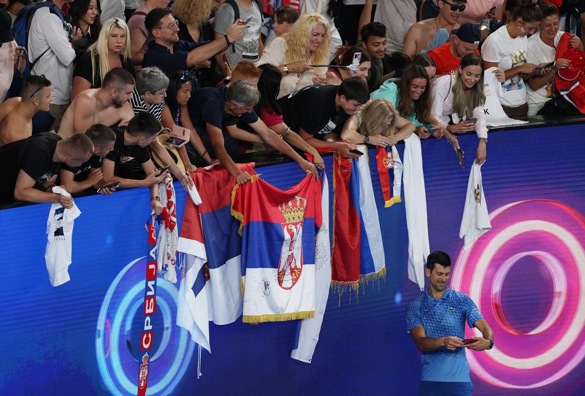 Novak Djokovic poses for a selfie with fans after winning his first round match.