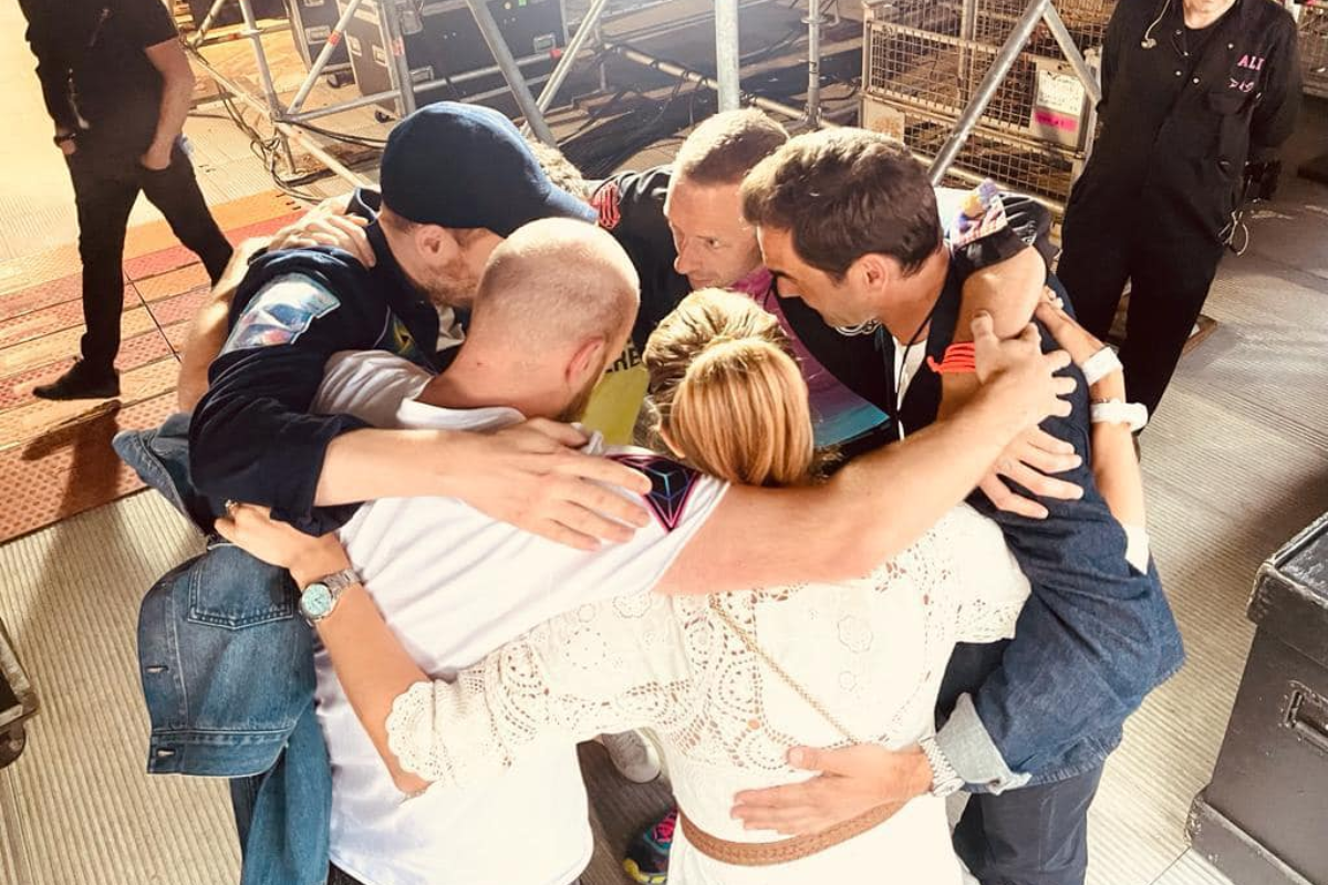 Members of Coldplay, Roger Federer and his wife Mirka in a huddle before his performance