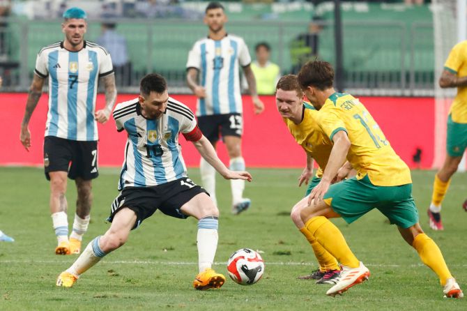 Argentina's Lionel Messi is challenged by Australia's Kye Rowles and Denis Genreau