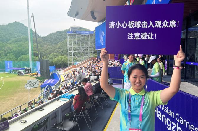 An Asian Games volunteer holds a sign warning spectators to beware of cricket balls being hit into the terraces at the stadium during the quarter-final match between India and Nepal at the Asian Games in Hangzhou, China October 3, 2023. Volunteers walked through the terraces shouting, 'Be careful of the ball,' and carried signs in Chinese saying: 'Take care to avoid.'