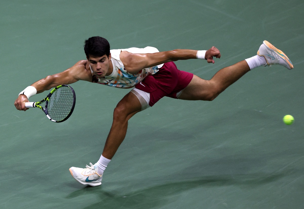 Carlos Alcaraz stretches to return against Daniil Medvedev.