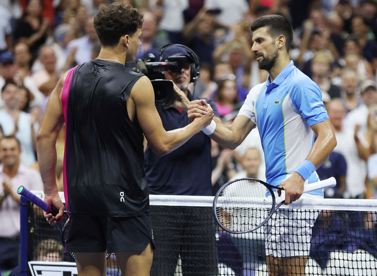 Novak Djokovic and Ben Shelton meet at the net after the match.