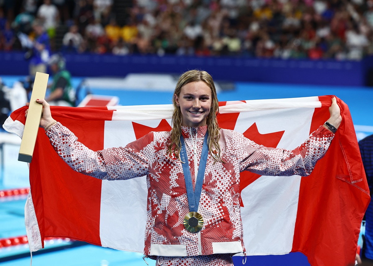 Canada's Summer McIntosh celebrates on the podium after winning the women's 200m Butterfly and establishing an Olympic record.