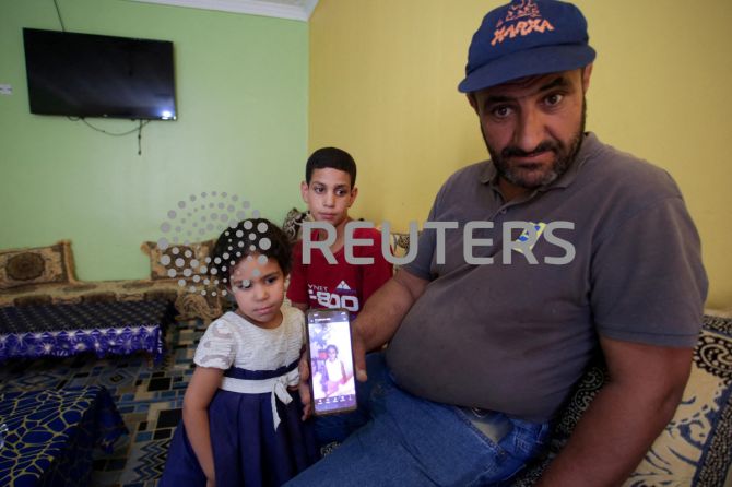 Amar, father of Algerian boxer Imane Khelif, sits with his children as he shows a picture of Imane when she was young, inside his house, in Tiaret province, Algeria 
