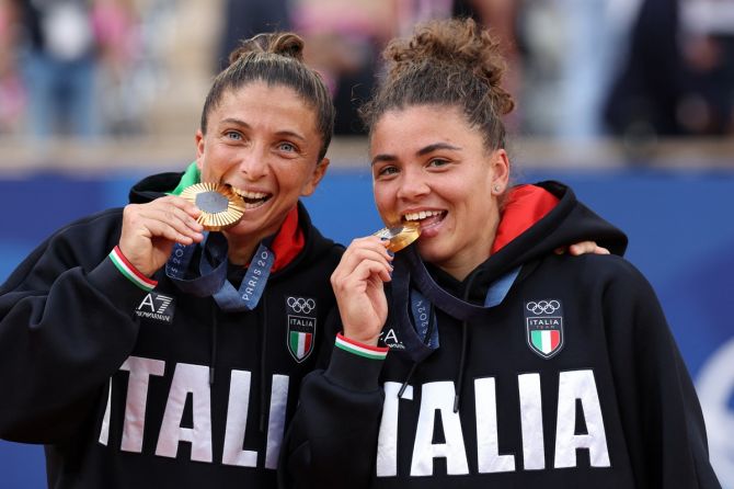 Italy's Jasmine Paolini and Sara Errani bite their gold medals at the Olympics Tennis Women's Doubles victory ceremony at Roland Garros stadium, Paris, on Sunday.