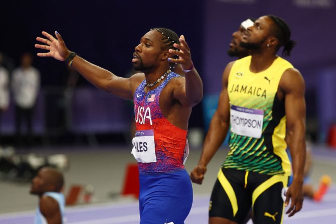 Noah Lyles celebrates after crossing the finish line as second-placed Kishane Thompson of Jamaica looks at the giant screen for the final results.