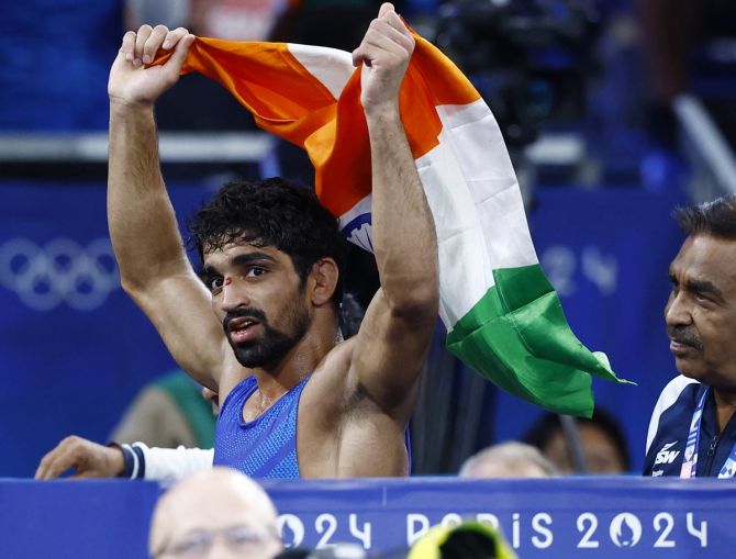 Aman Sehrawat celebrates with the tricolour after the bout.