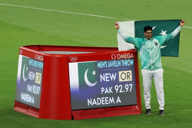 Paris Olympics champion and Pakistan Arshad Nadeem poses beside the screen displaying his new Olympic record after the javelin throw final on Thursday