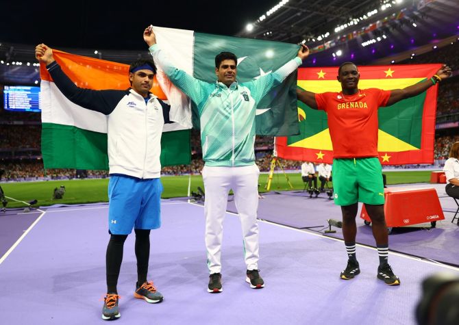 Gold medallist Arshad Nadeem, Neeraj Chopra (silver) and Anderson Peters (bronze) celebrate with their national flags at te conclusion of the men's Javel Throw final.