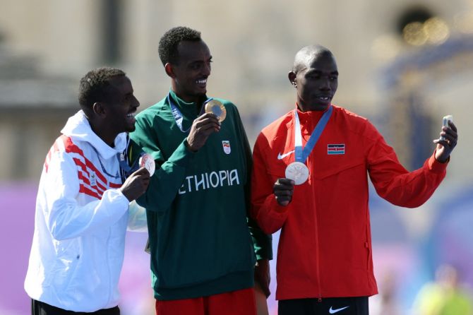 Gold medallist Tamirat Tola of Ethiopia, silver medallist Bashir Abdi of Belgium and bronze medallist Benson Kipruto of Kenya pose for a selfie with their medals