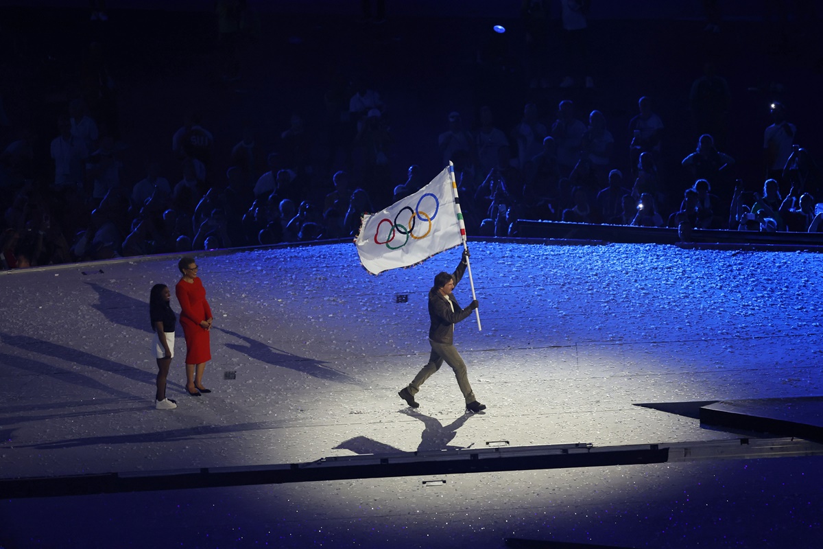 United States gymnastics queen Simone Biles and Los Angeles Mayor Karen Bass hand over the Olympic flag off to Tom Cruise.