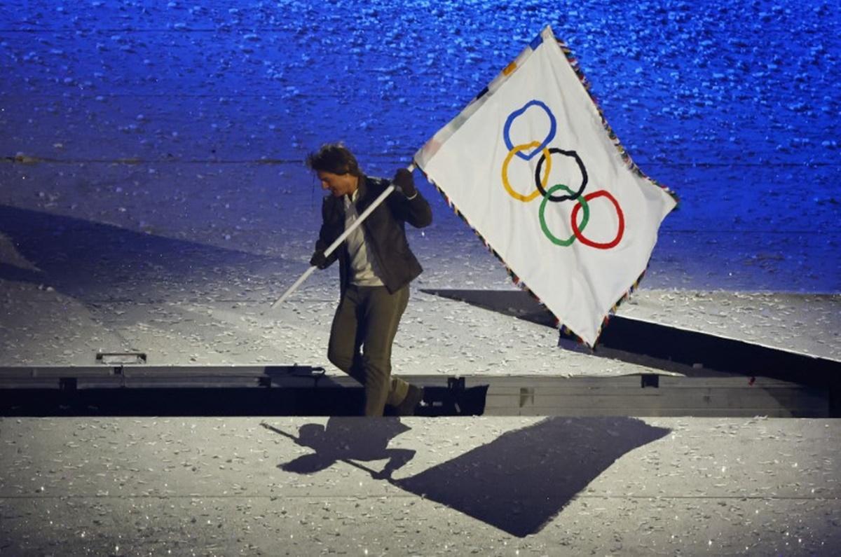 Tom Cruise receives the Olympic flag.