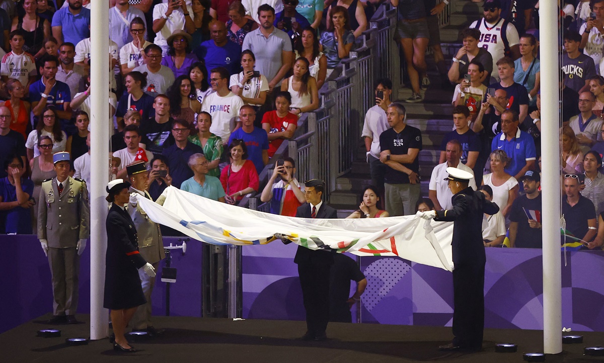 The Olympic flag is lowered and folded for the handover. 