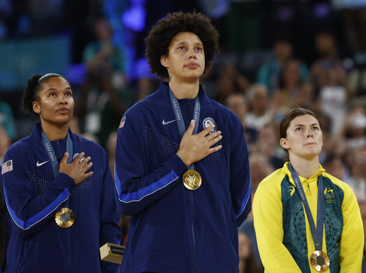 A teary-eyed Brittney Griner and Alyssa Thomas of the United States with bronze medallist Jade Melbourne of Australia on the podium at the Olympics women's basketball victory ceremony at Bercy Arena, Paris, on Sunday.