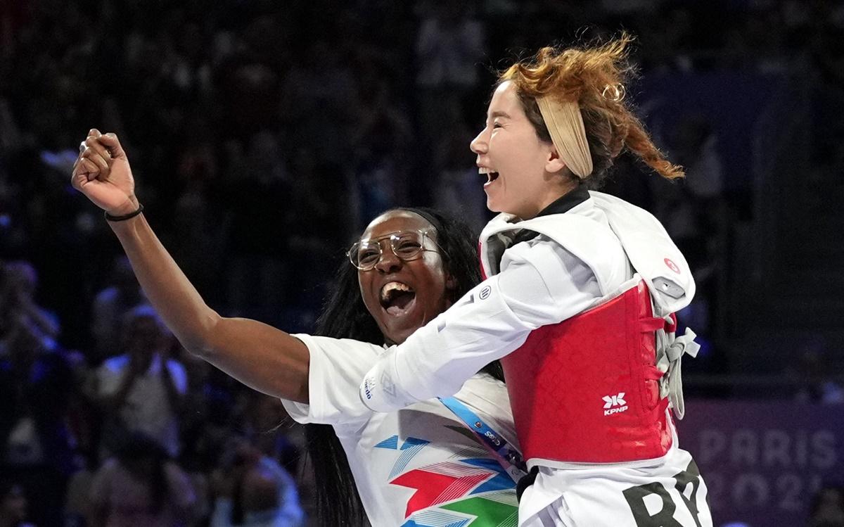 Zakia Khudadadi celebrates with her trainer after being declared winner following the withdrawal of Morocco's Naoual Laarif.