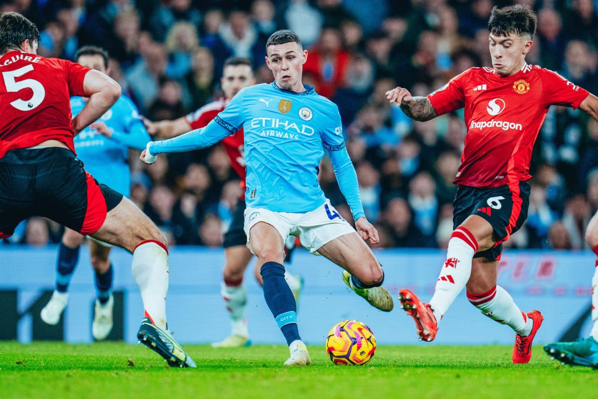 Manchester City's Phil Foden is challenged by Manchester United Harry McGuire while attempting at shot at goal