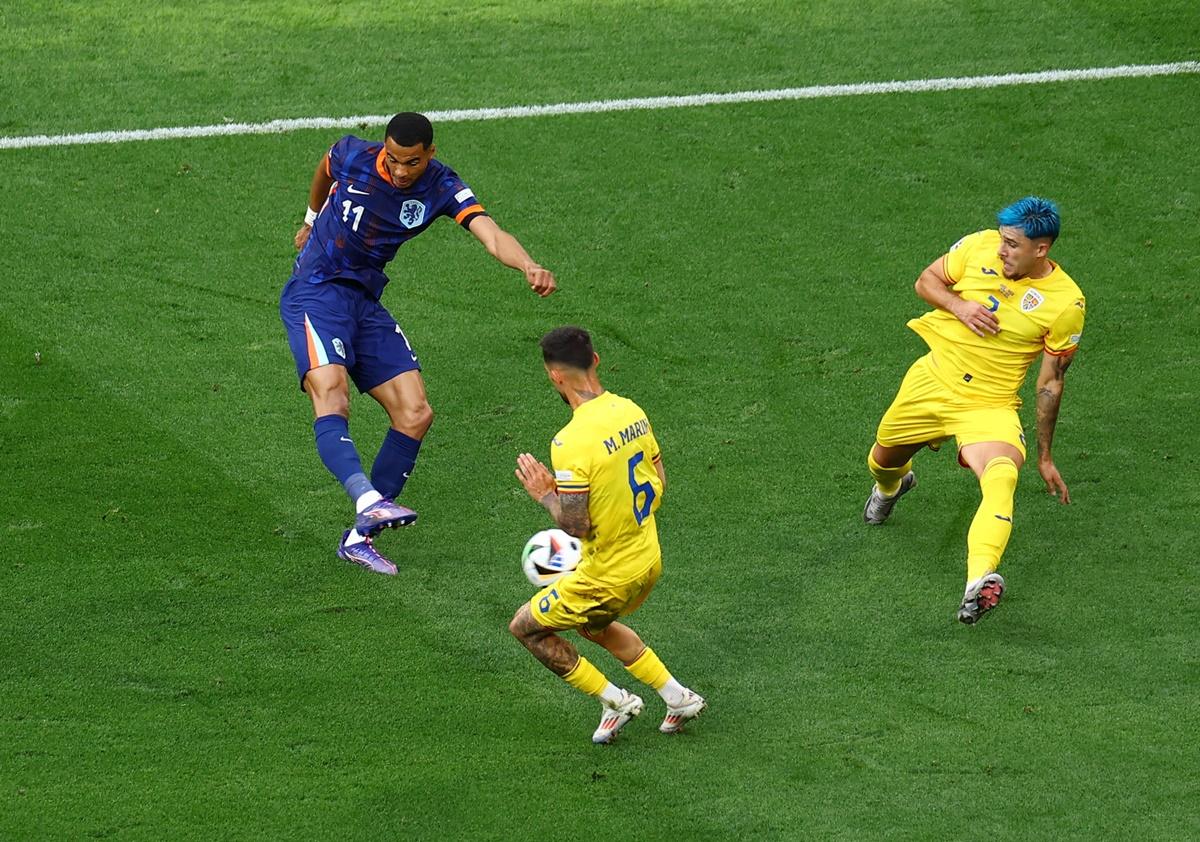 Cody Gakpo fires the ball past Romania's Marius Marian to put the Netherlands ahead in the match.