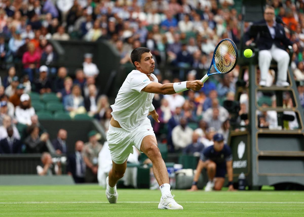 Alexei Popyrin rushes to the net to finish off a point against Novak Djokovic.