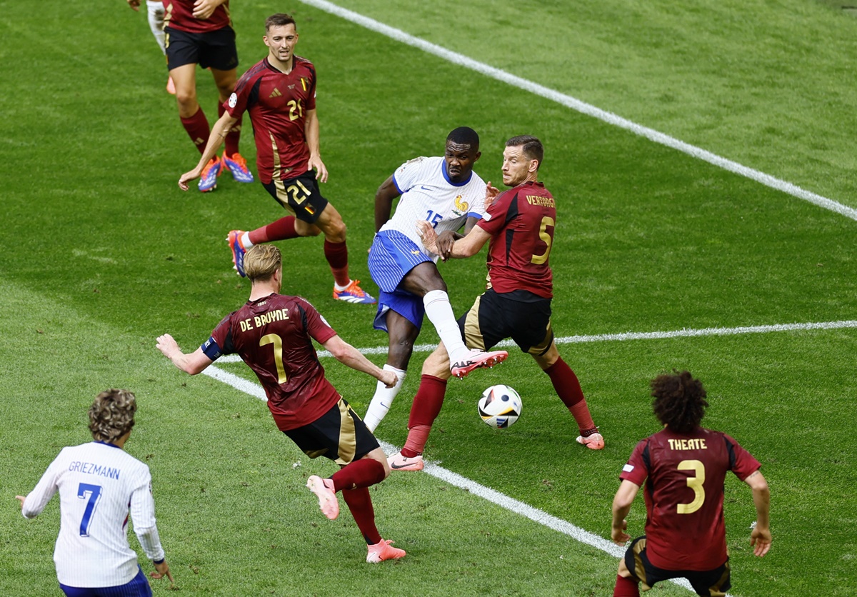 France's Marcus Thuram (No. 15) shoots at goal under pressure from Belgium's Jan Vertonghen and Kevin De Bruyne.