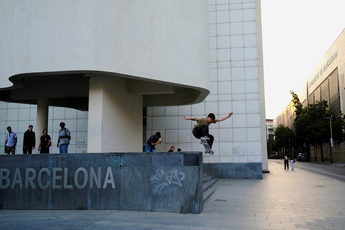 A young skater performs a trick, known as a frontside ollie, as his friend records him in front of MACBA (Barcelona Contemporary Art Museum), known as the Mecca of skateboarding with its unique architecture that's full of features that are perfect for every style, transforming it into a dream location that is iconic to skaters worldwide, in Barcelona, Spain