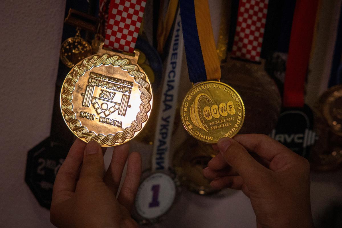 Diana, the widow of the late Olympic weightlifter Oleksandr Pielieshenko, who was killed fighting against Russia's invasion, looks at his medals in their apartment in Kyiv, amid Russia's attack on Ukraine