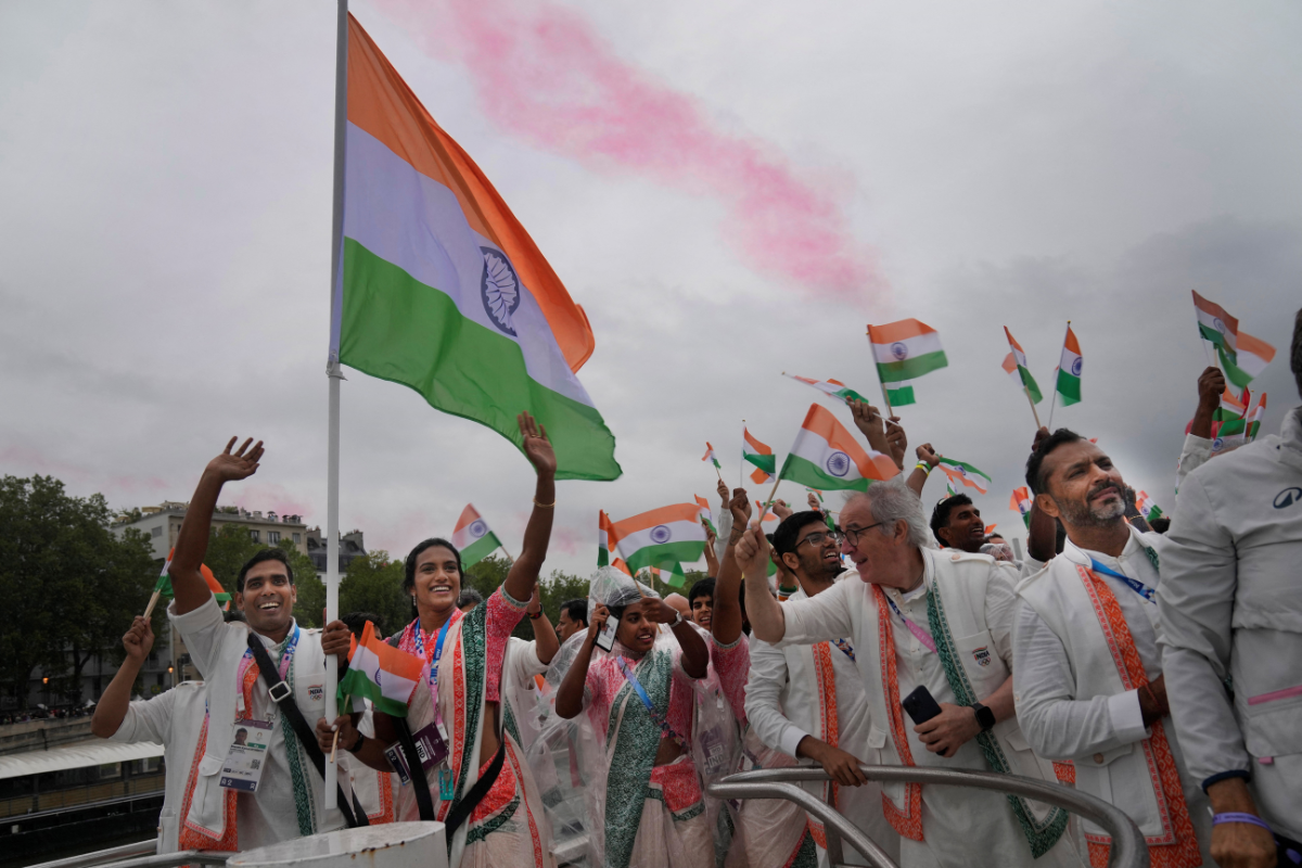 Indian athletes wave their national flags from a boat on the Seine River during the opening ceremony of the Paris 2024 Olympics
