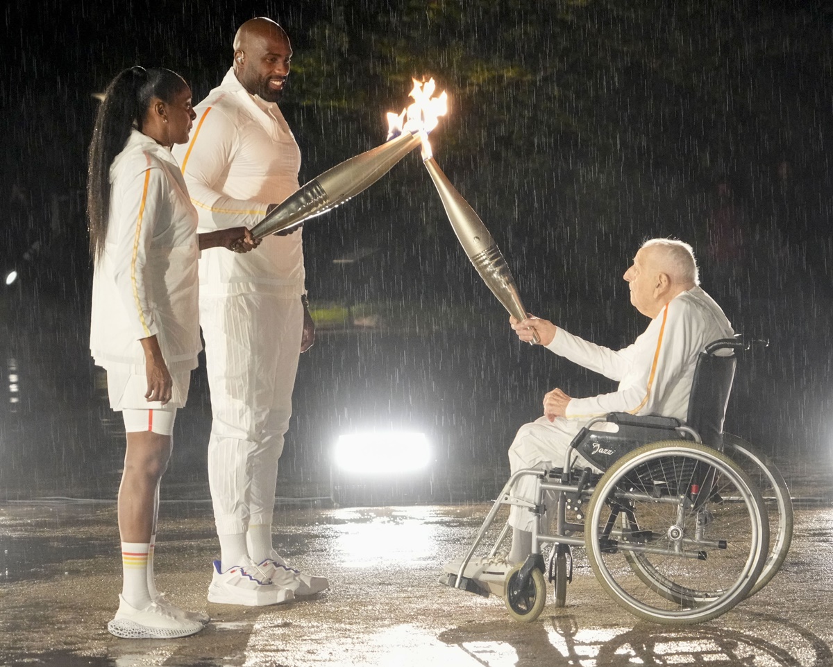 French cyclist Charles Coste (from right) lights the torches of judoka Teddy Riner and sprinter Marie-José Pérec during the Opening Ceremony.