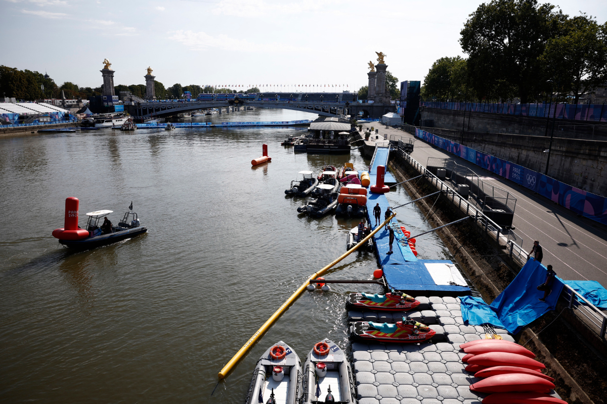 General view of the river Seine and Alexander III Bridge as workers remove a buoy after Triathlon training was cancelled amid water quality concerns