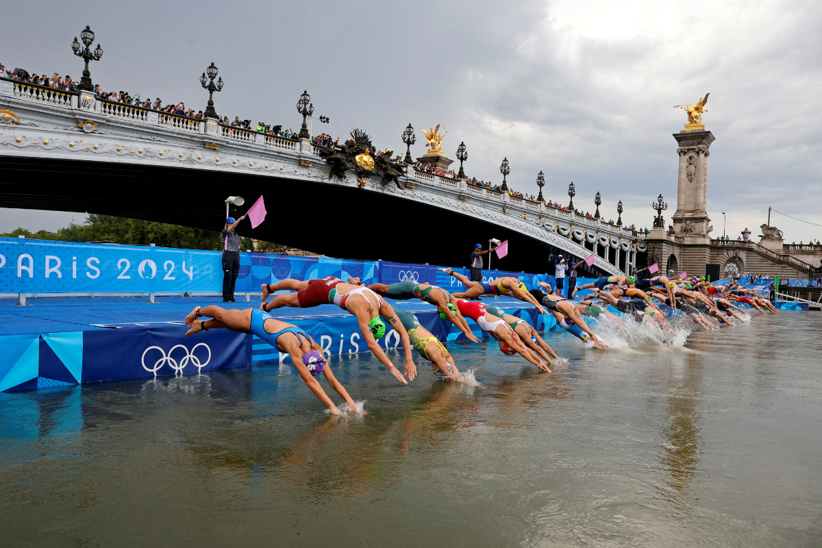 Swimmer dive into the Seine as the women's Individual Triathlon race commences at Alexander III Bridge, Paris, France, on Wednesday 