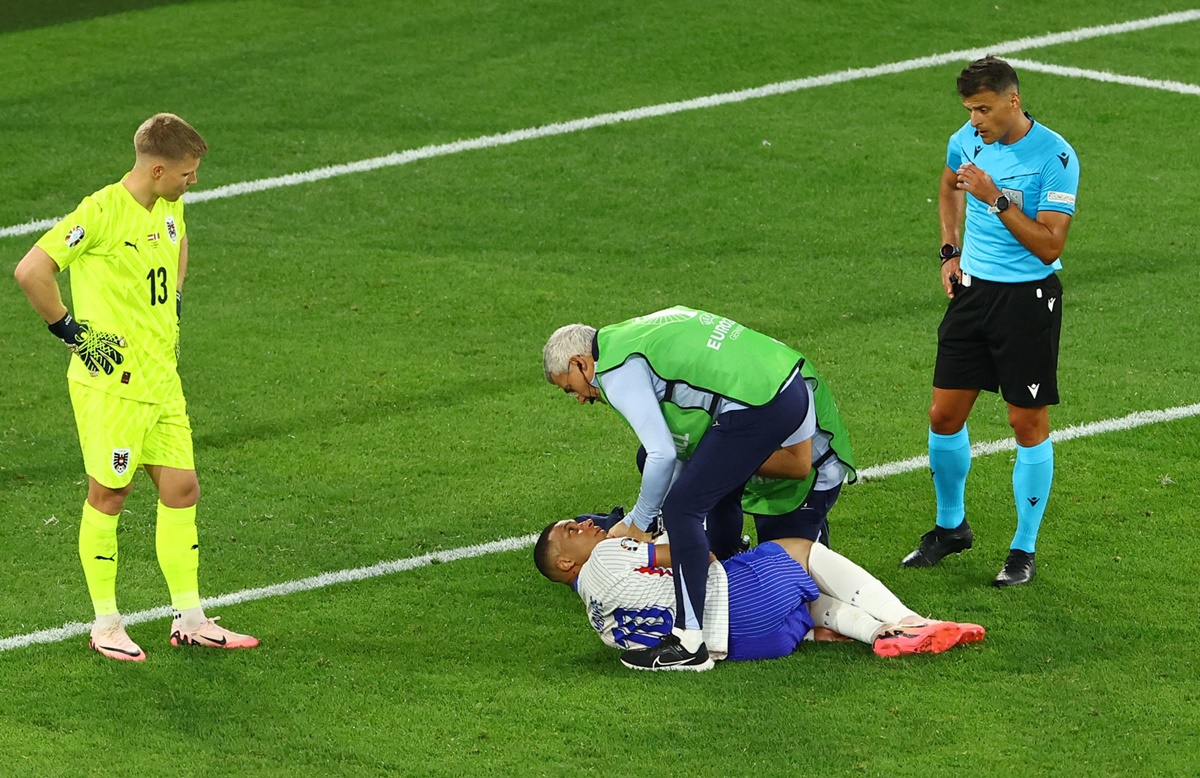 Kylian Mbappe receives medical attention after sustaining an injury on his nose as Austria's goalkeeper Patrick Pentz looks on.