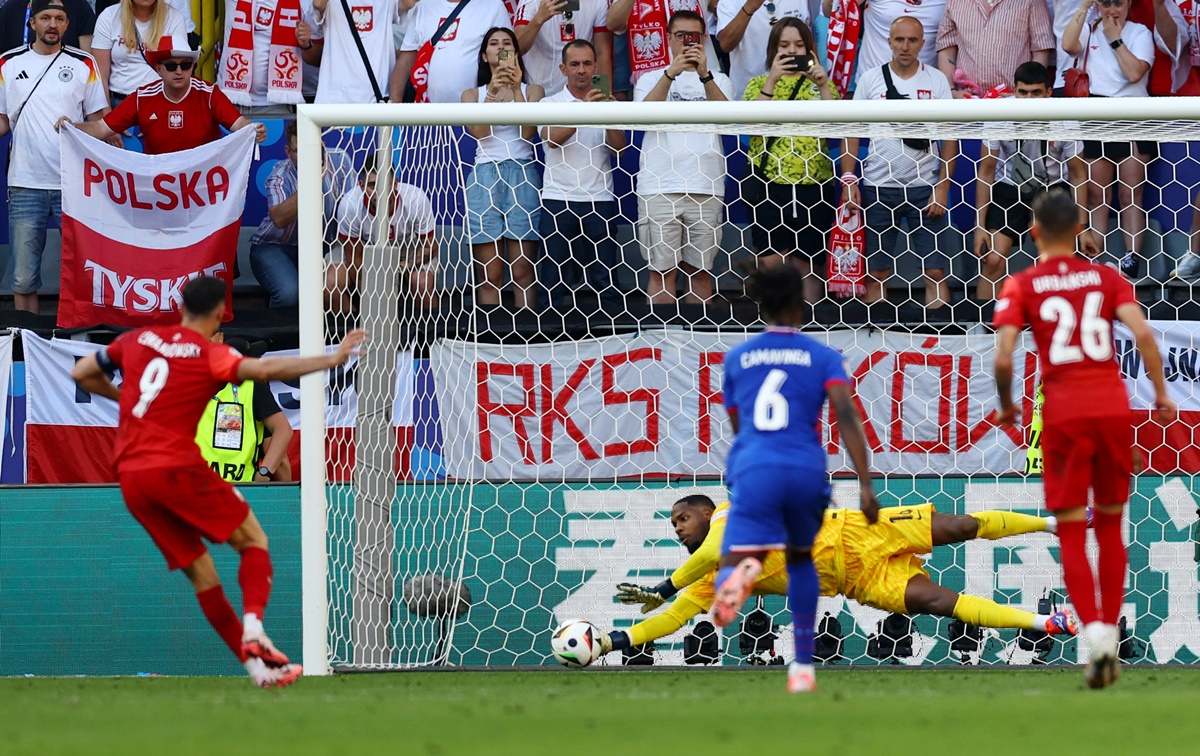 France's goalkeeper Mike Maignan saves a penalty from Robert Lewandowski, which had to be retaken.