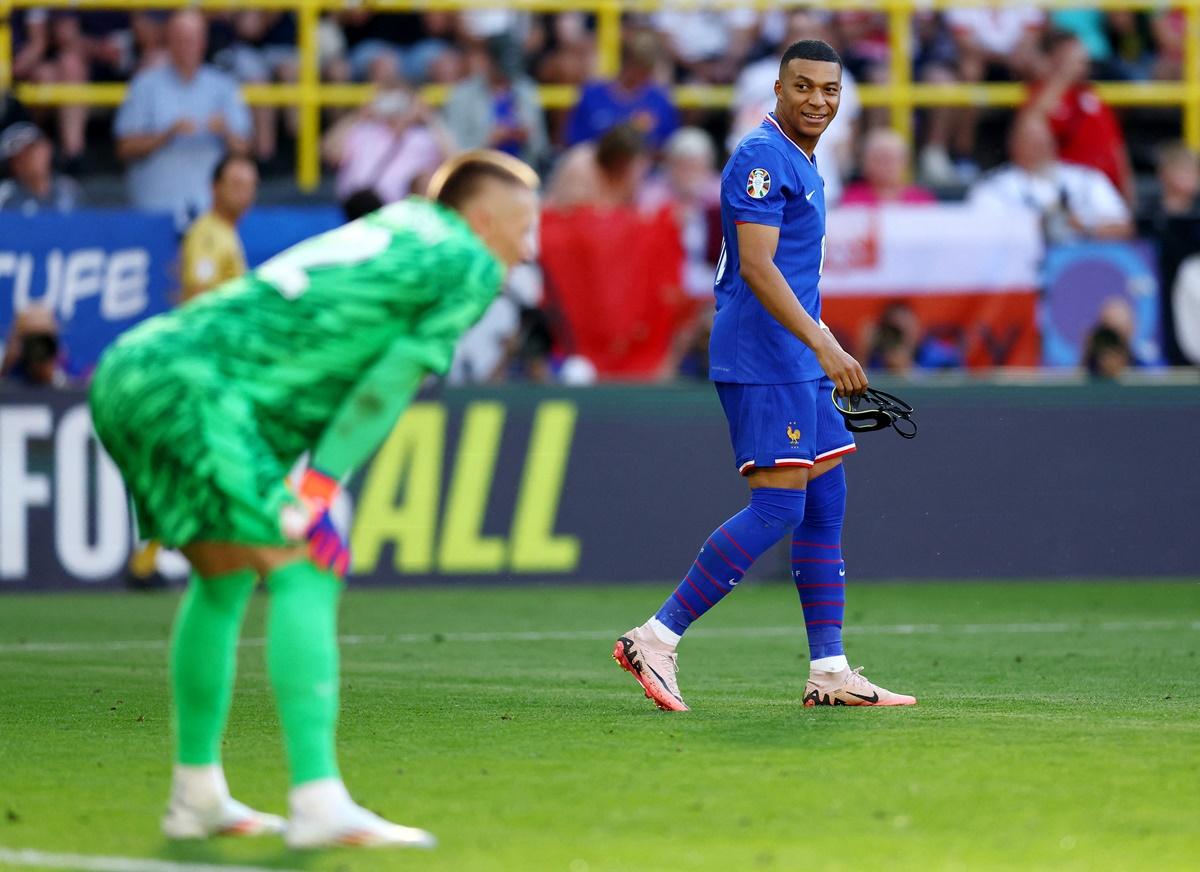 Kylian Mbappe celebrates scoring as Poland's goalkeeper Lukasz Skorupski looks on.