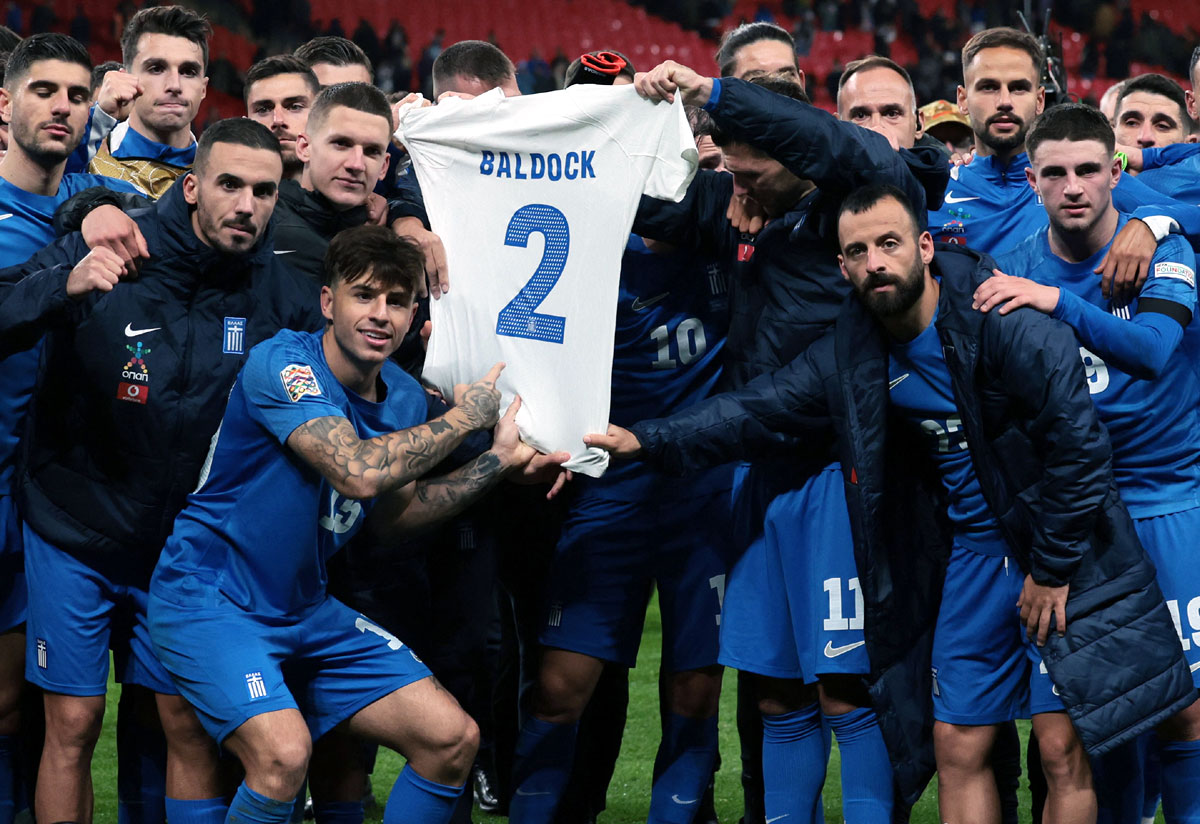 Greece players hold up a shirt in a tribute to George Baldock after the match