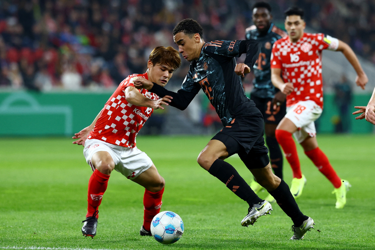 Bayern Munich's Jamal Musiala wins the ball against 1. FSV Mainz 05's Kaishu Sano