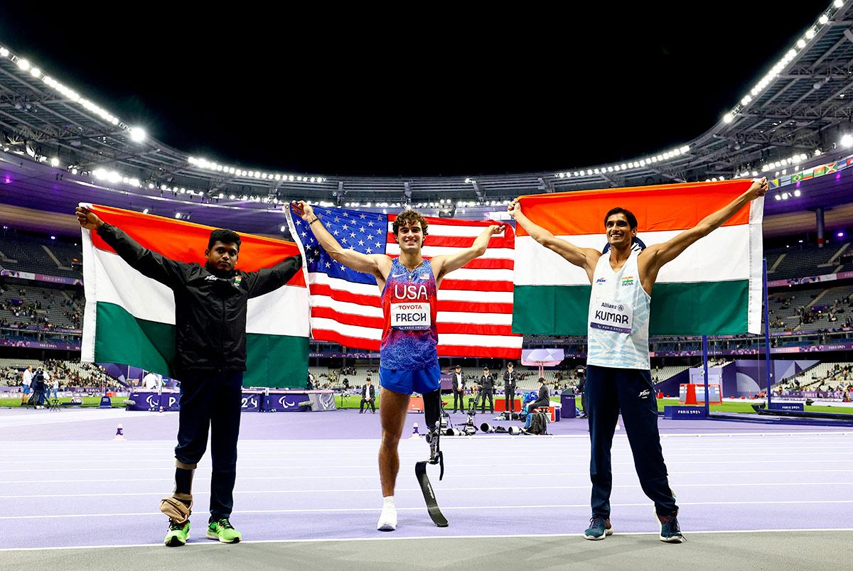 Ezra Frech of US celebrates winning gold with silver medallist Sharad Kumar of India and bronze medallist Mariyappan Thangavelu of India