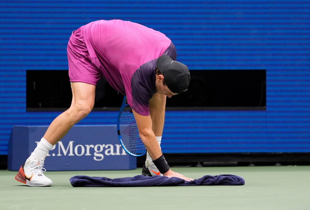 Jack Draper cleans up after vomiting on court in the second set.