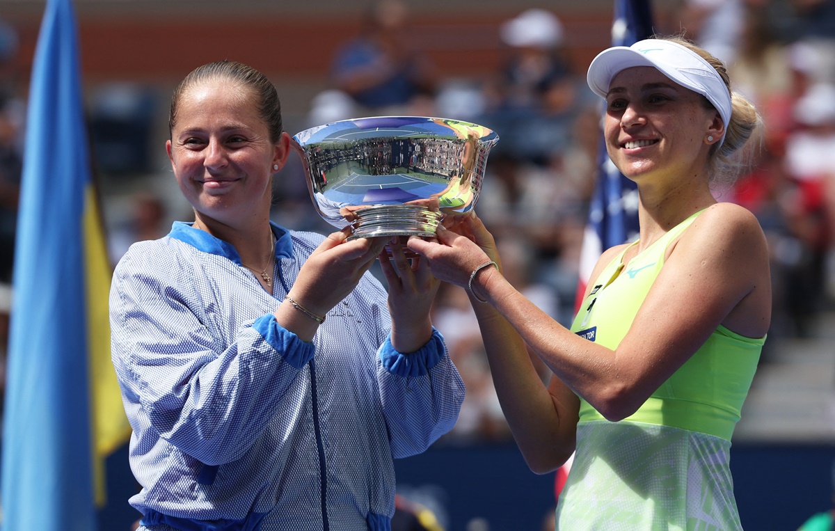 Jelena Ostapenko and Ukraine's Lyudmyla Kichenok hoist the trophy after the presentation ceremony.