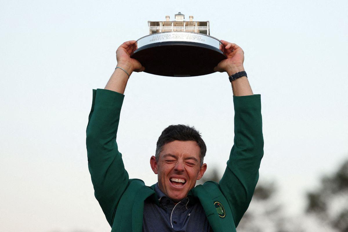 Northern Ireland's Rory McIlroy celebrates with his green jacket and the trophy after winning The Masters and completing a career grand slam