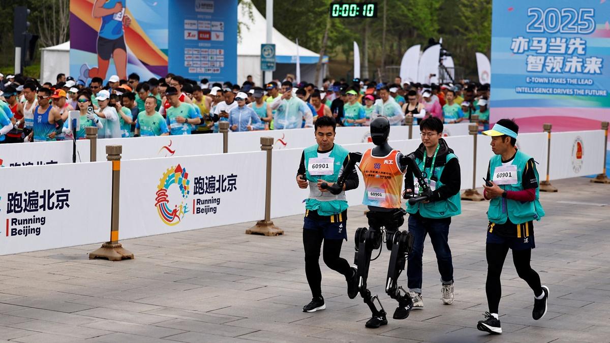 Engineers run with humanoid robot 'Tiangong' as it participates along with human runners in the E-Town Half Marathon & Humanoid Robot Half Marathon in Beijing, China, on Saturday.