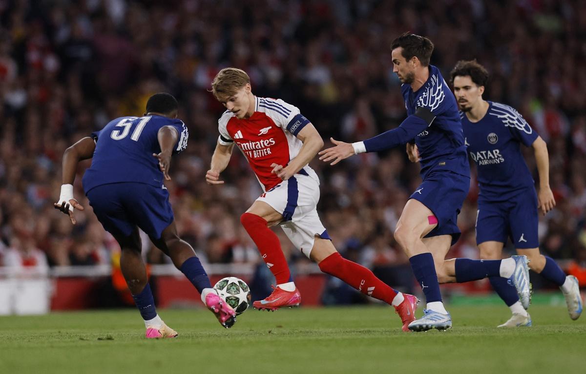 Arsenal's Martin Odegaard in challenged by Paris St Germain's Willian Pacho and Fabian Ruiz as he tries to break through.